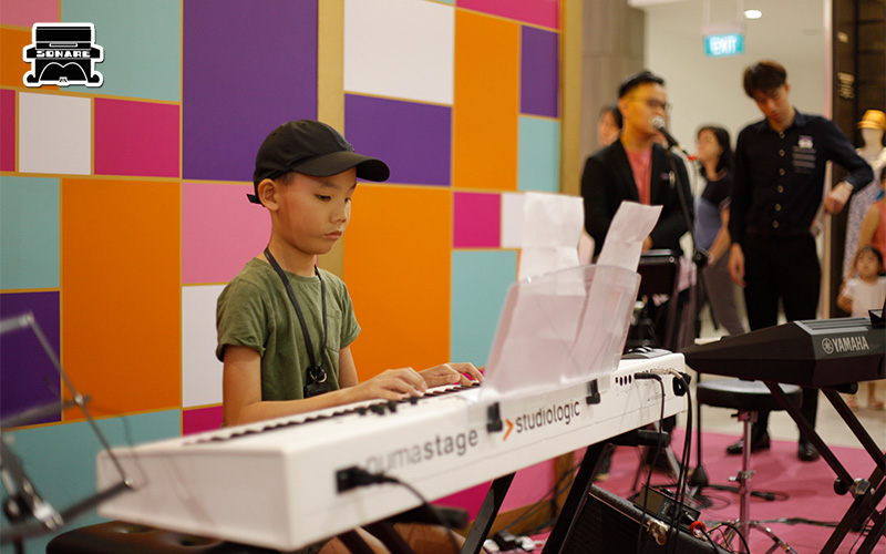 Boy focusing while playing a song on a digital piano.