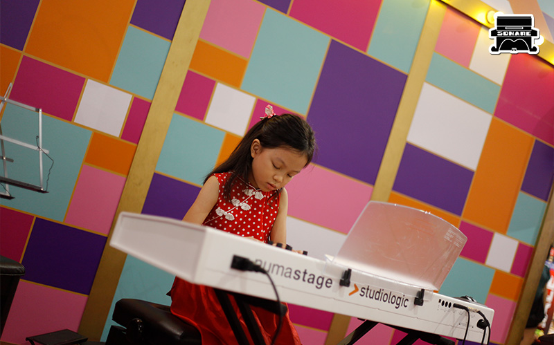 Child intently practicing piano at Sonare Music School.