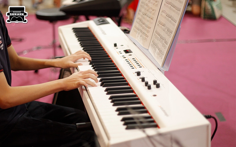 Hands playing an electric piano during performance.