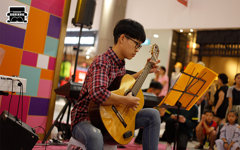 Student performing with a guitar at a Sonare event.