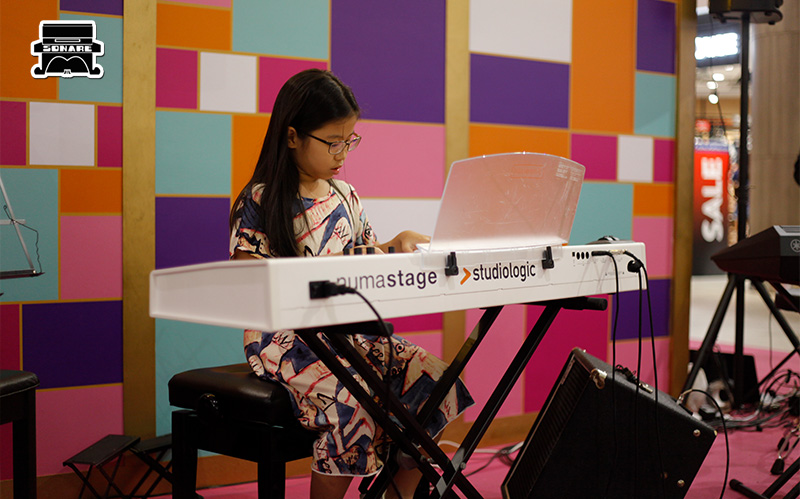 Young girl focused on learning piano.