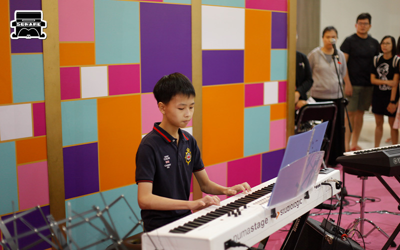 Young musician reading sheet music and playing piano.