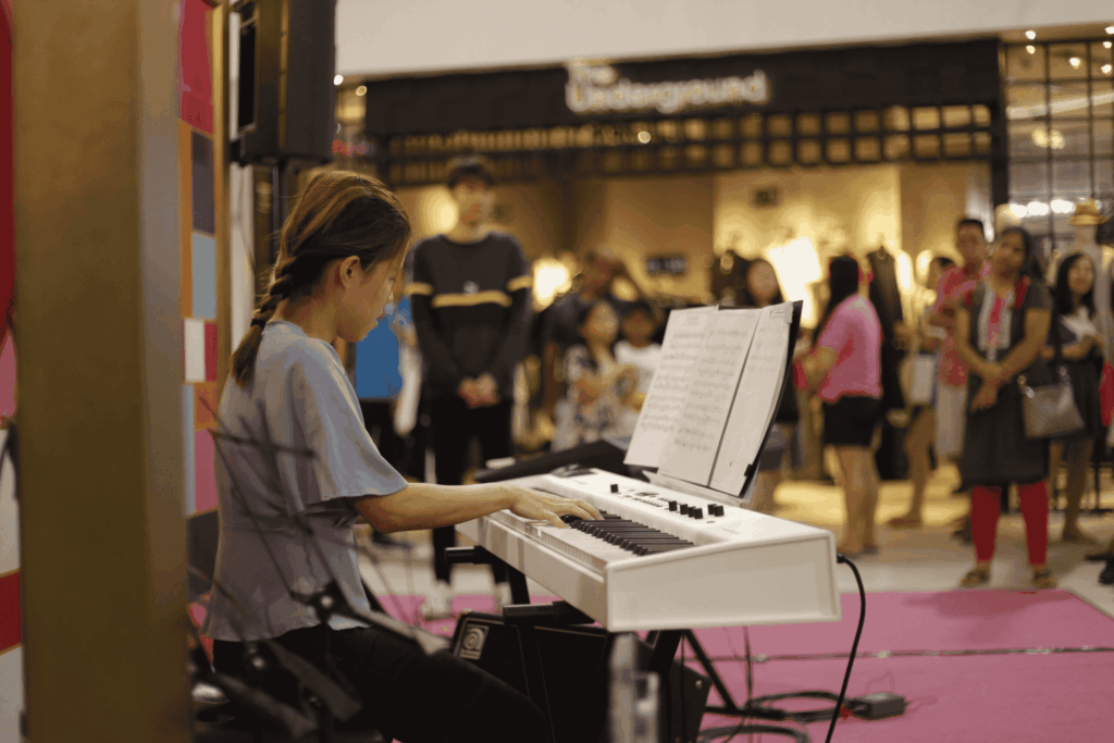 A young woman with braids plays a white keyboard onstage.