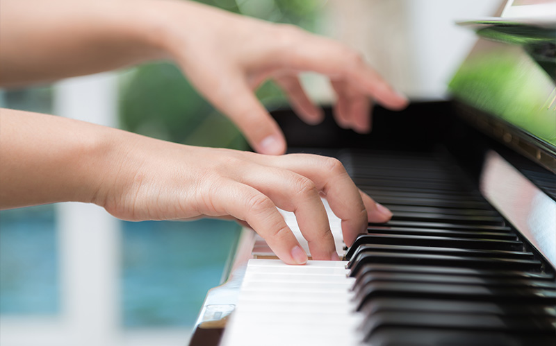 Close-up of a child's hands playing the piano keys.