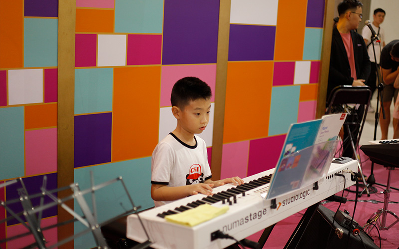 Child playing an electronic keyboard during a Sonare music class.