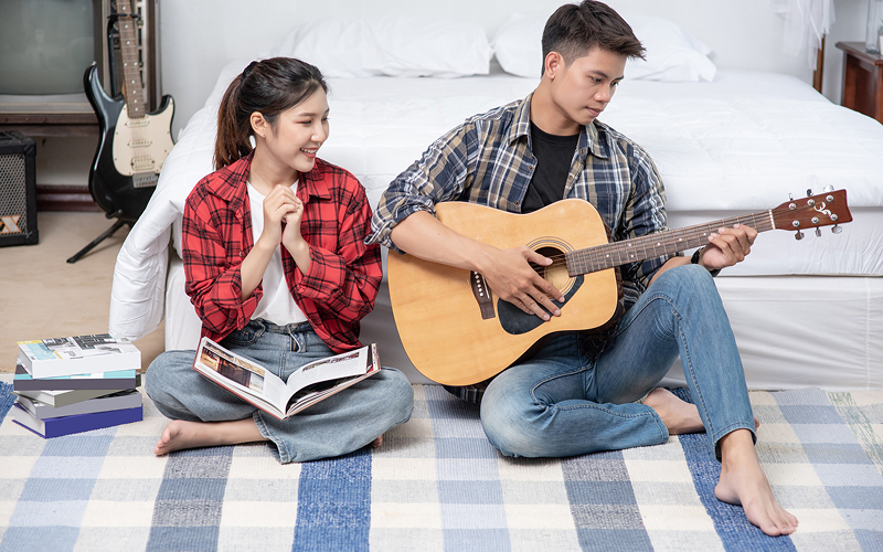 Teen musician playing acoustic guitar skills to impress a peer.
