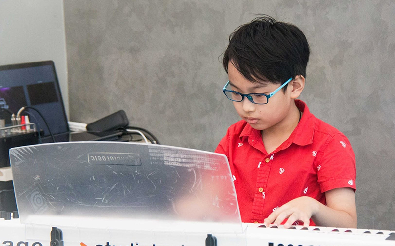 Young child practicing keyboard to learn from famous musicians.