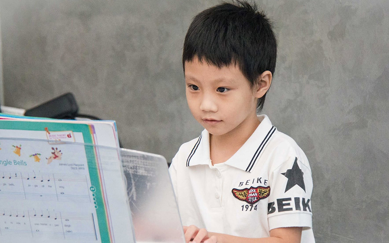 Young student reading keyboard music for child music lessons.